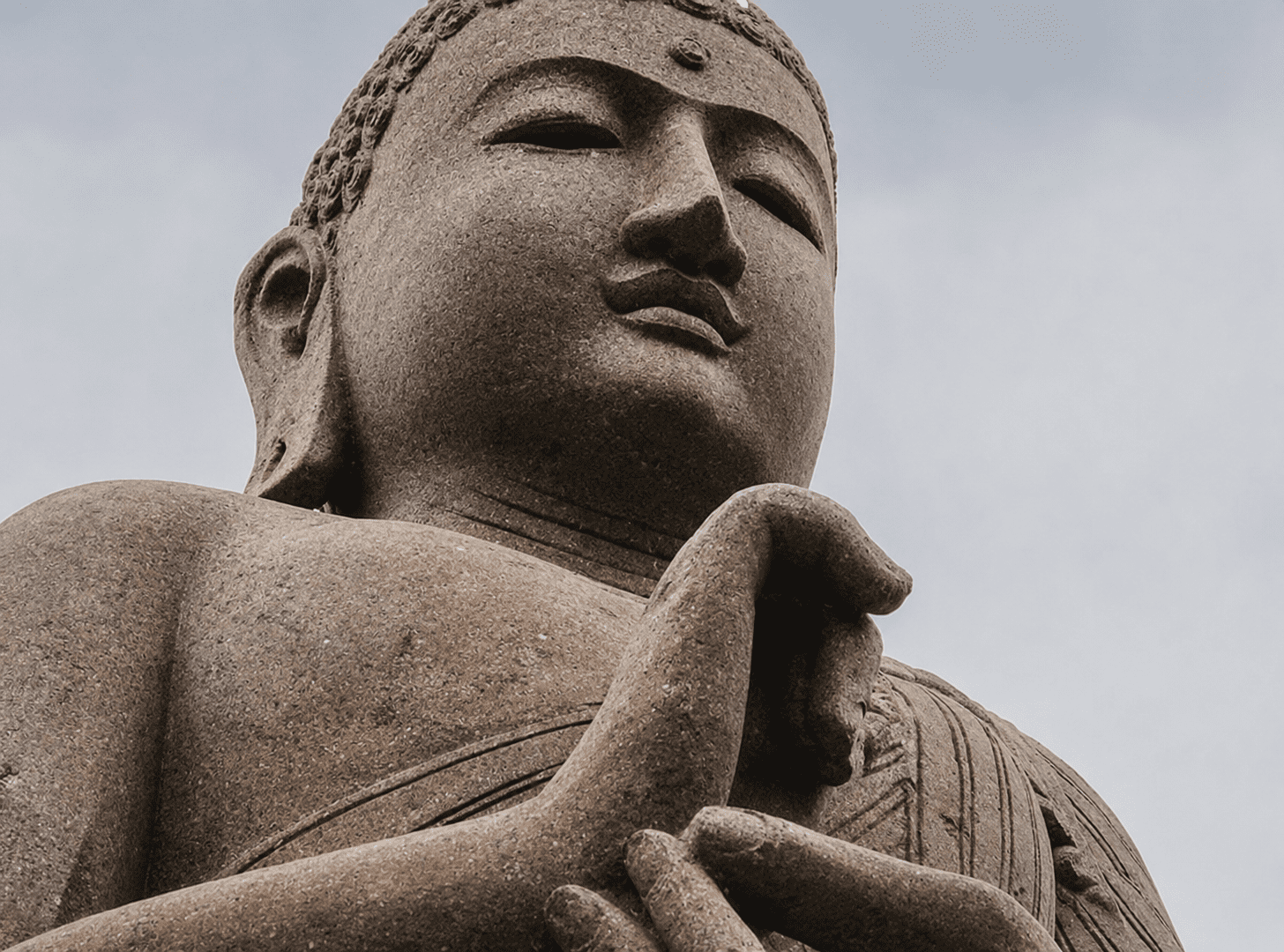 Stone Buddha statue with hands in gesture.
