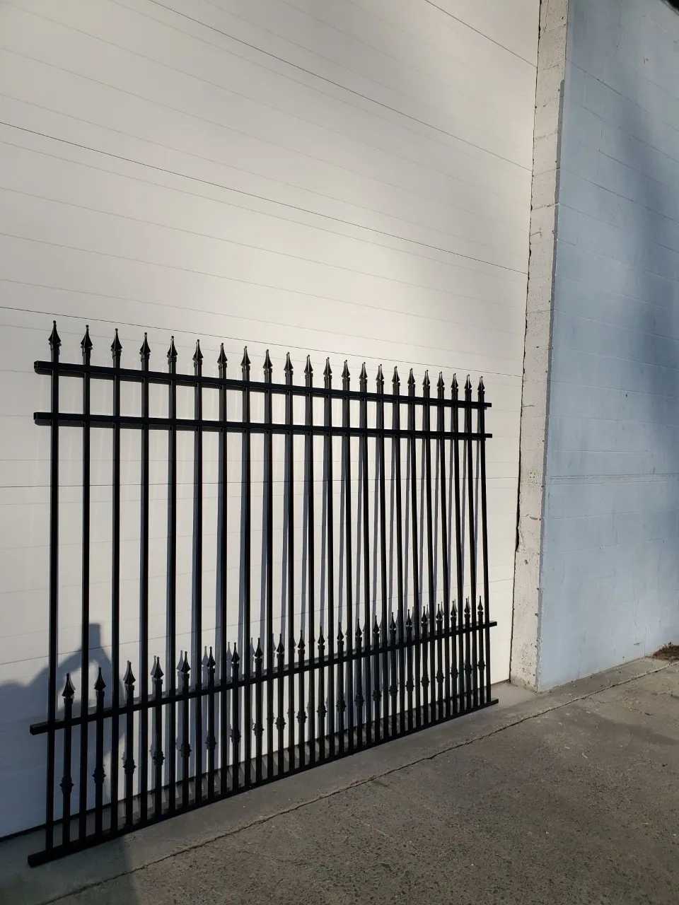 Black metal fence leaning against white wall.
