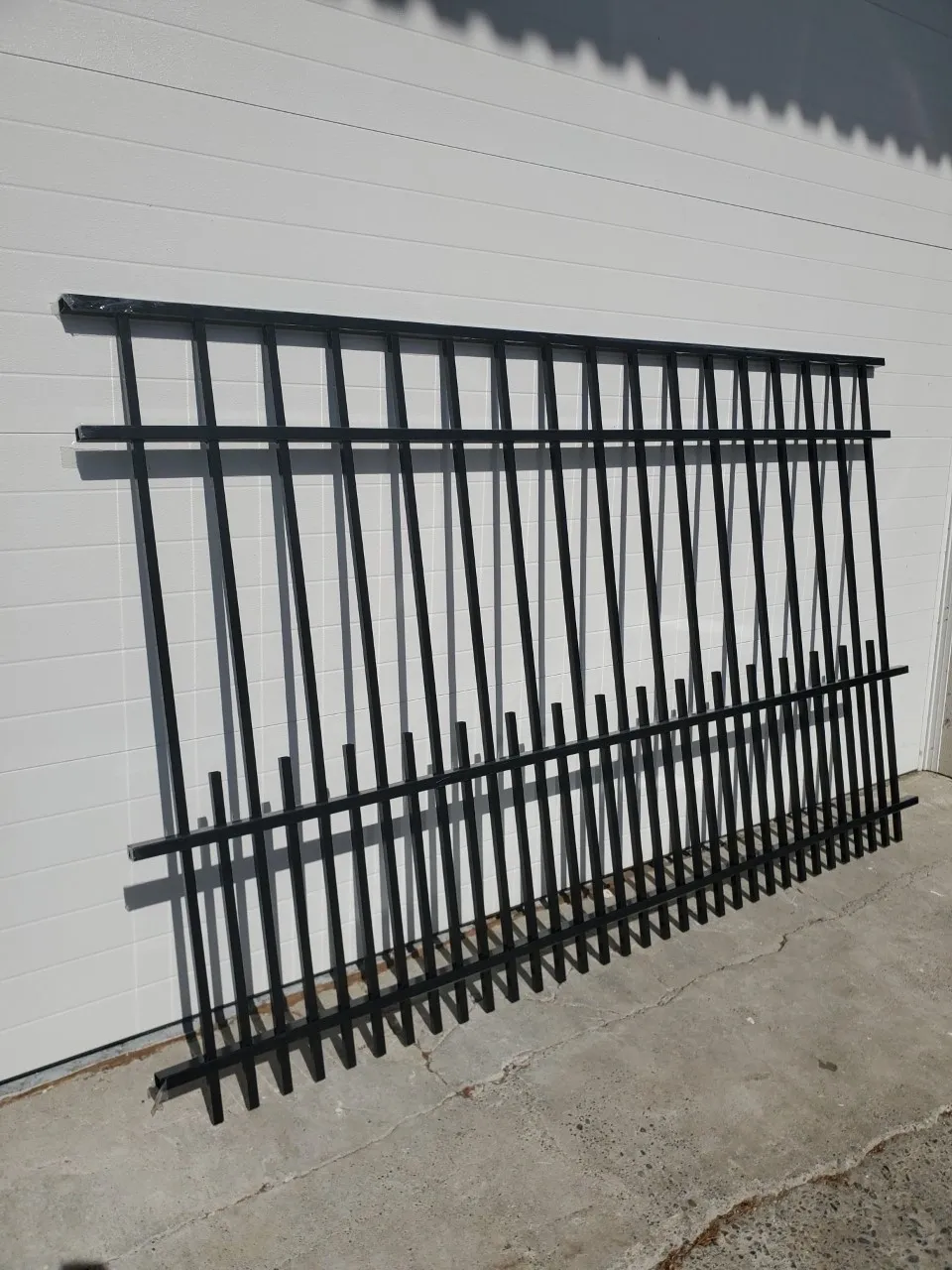 Metal fence leaning against white wall.