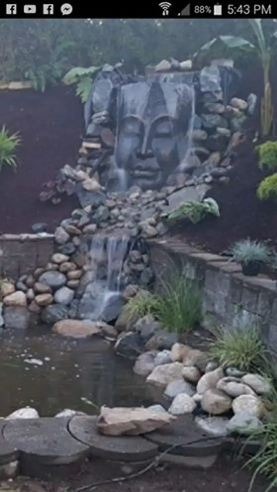 Waterfall with stone face and pond.