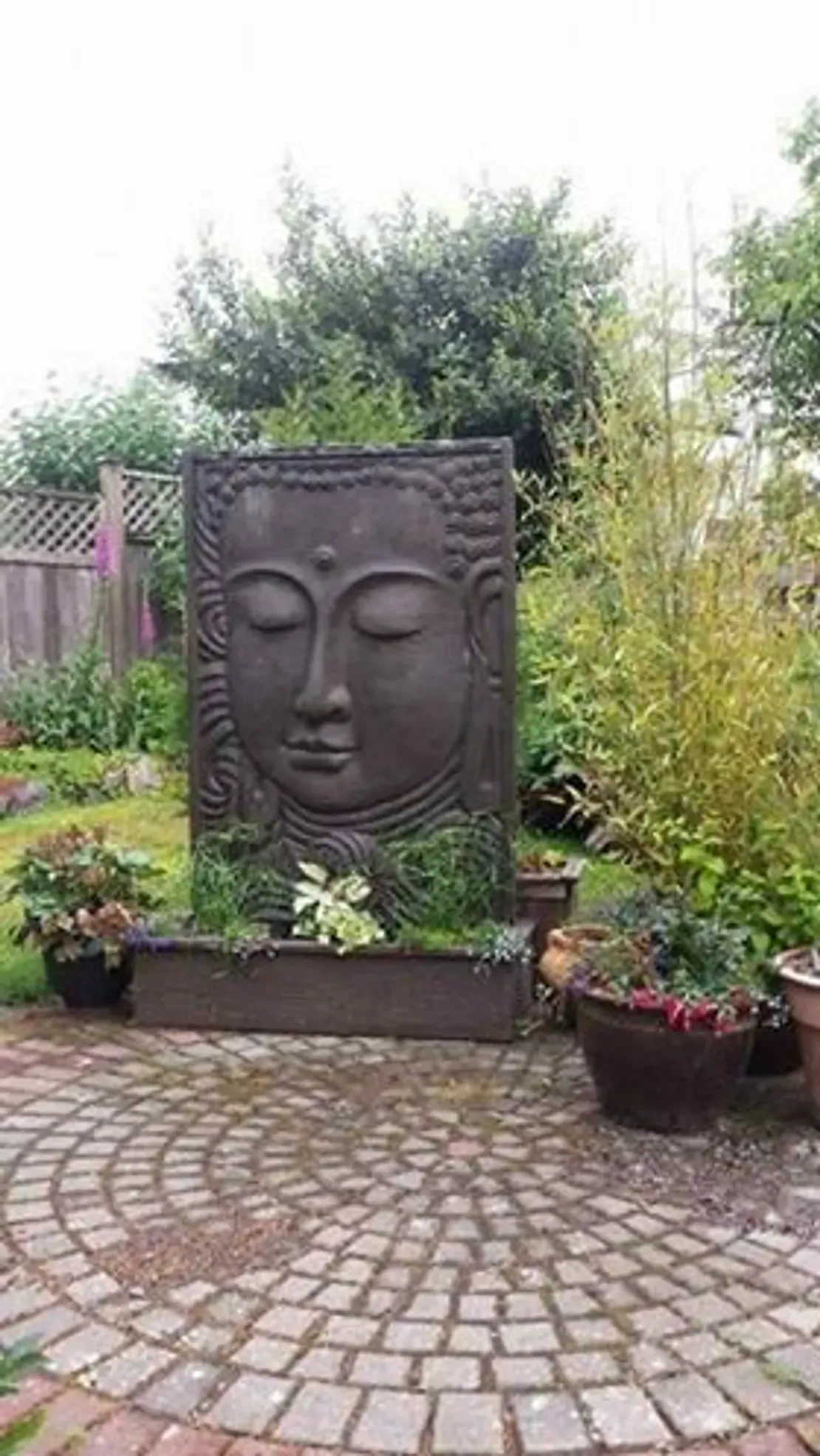 Buddha face sculpture in a garden setting.
