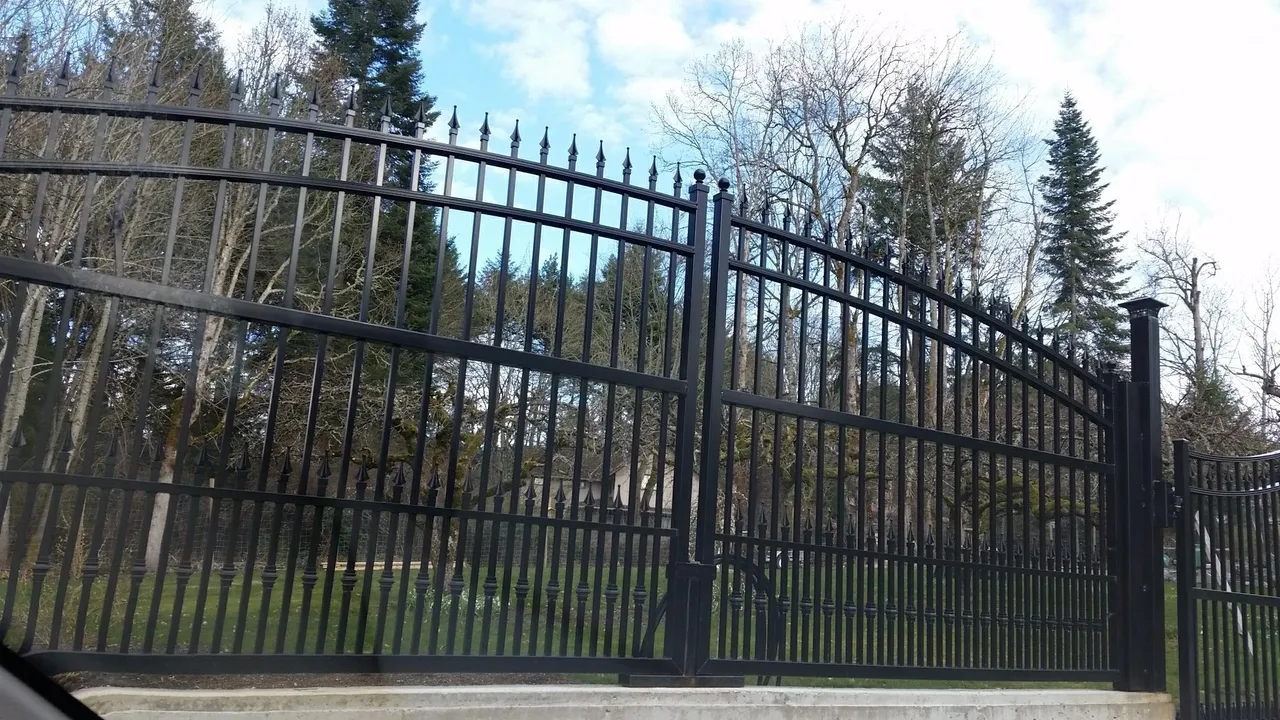 Black iron fence with trees in background.