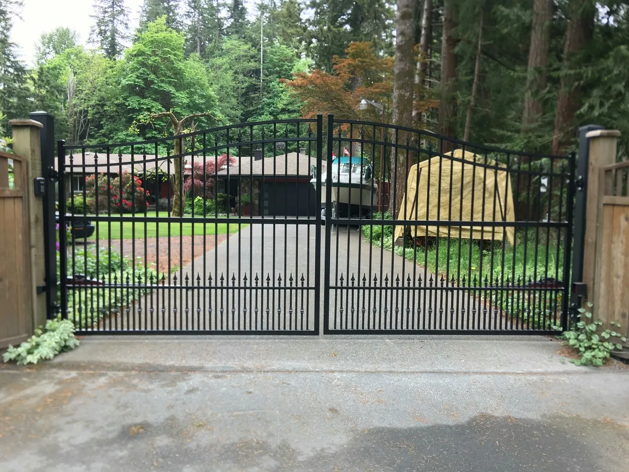 Black metal gate in forested residential area.
