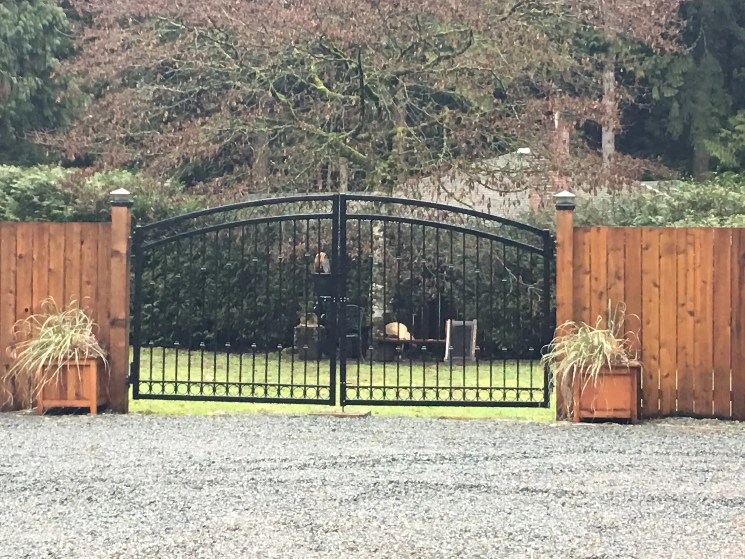 Black metal gate with wooden fence.