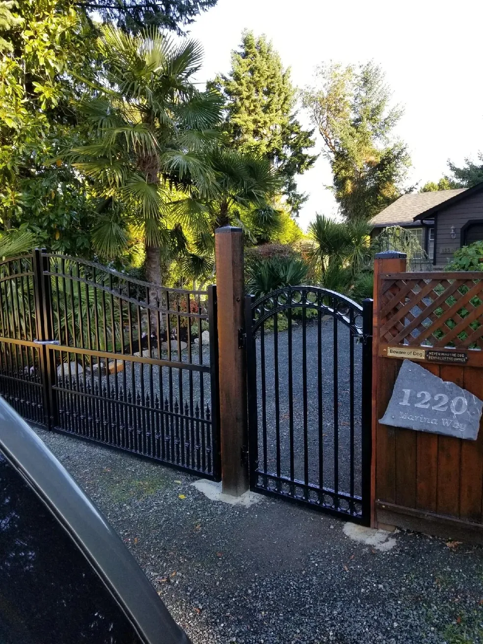 Black metal gate with wooden fence entrance.