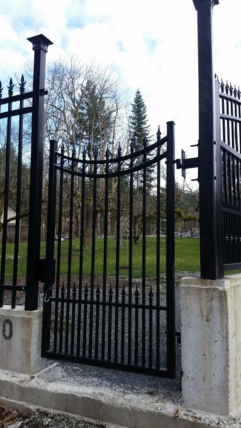 Black metal gate with trees in background.